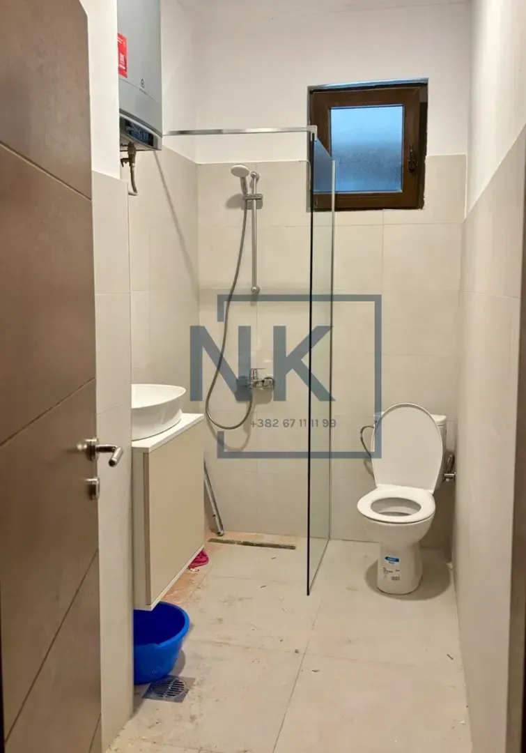 Bathroom equipped with a glass-partition shower cabin, washbasin, and toilet.