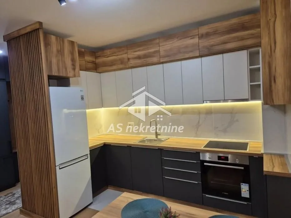Modern kitchen with wooden elements, built-in appliances, and a refrigerator.