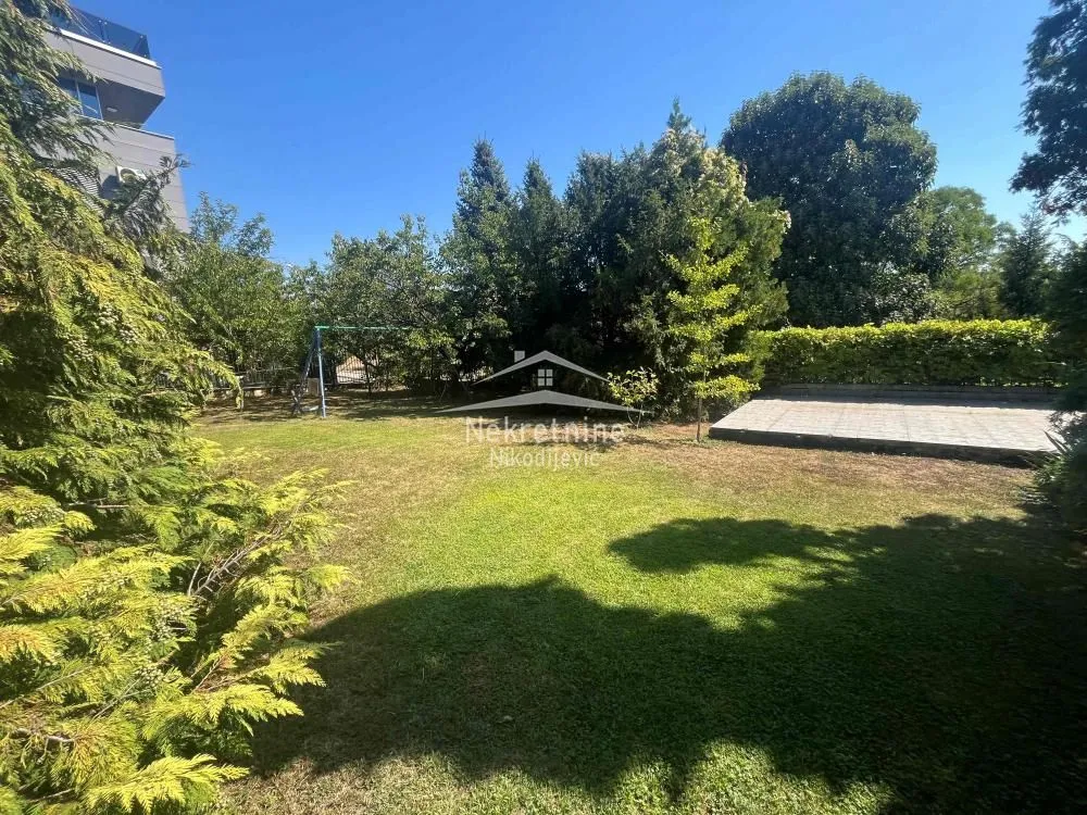 View of a spacious green yard with a lawn and trees.