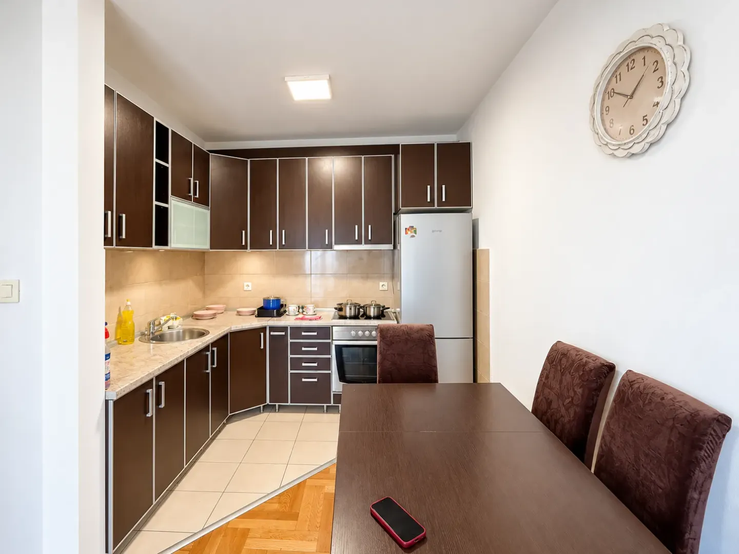 Dark-toned kitchen with a dining table and a refrigerator.