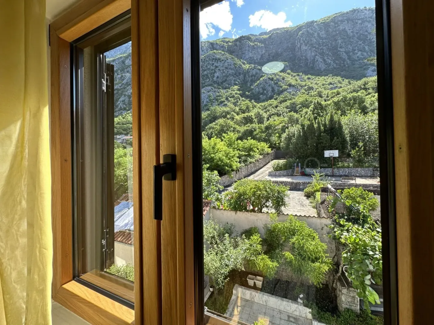 View through the window of the yard and surrounding mountains.