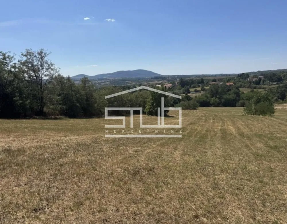Pogled na zelenu parcelu sa prirodom u okruženju.