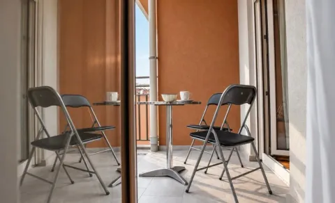 Manji balkon sa stolom i dvije stolice, djelimično prikazan kroz staklena vrata. - image 6