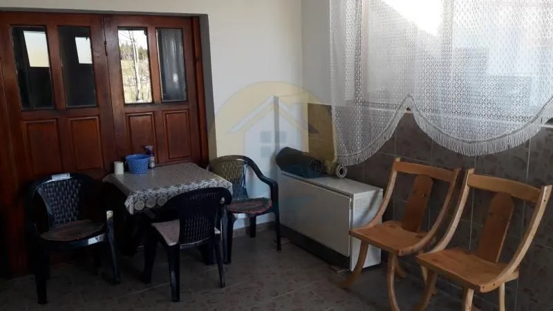 Enclosed terrace with a dining table, chairs, and a window with a curtain.