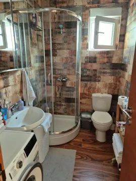 Small bathroom with a shower cabin, sink, toilet, and washing machine. - image 7
