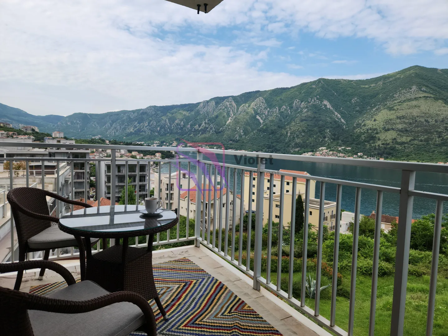 Namješten balkon sa stolom, stolicama i lijepim pogledom na more i planine.