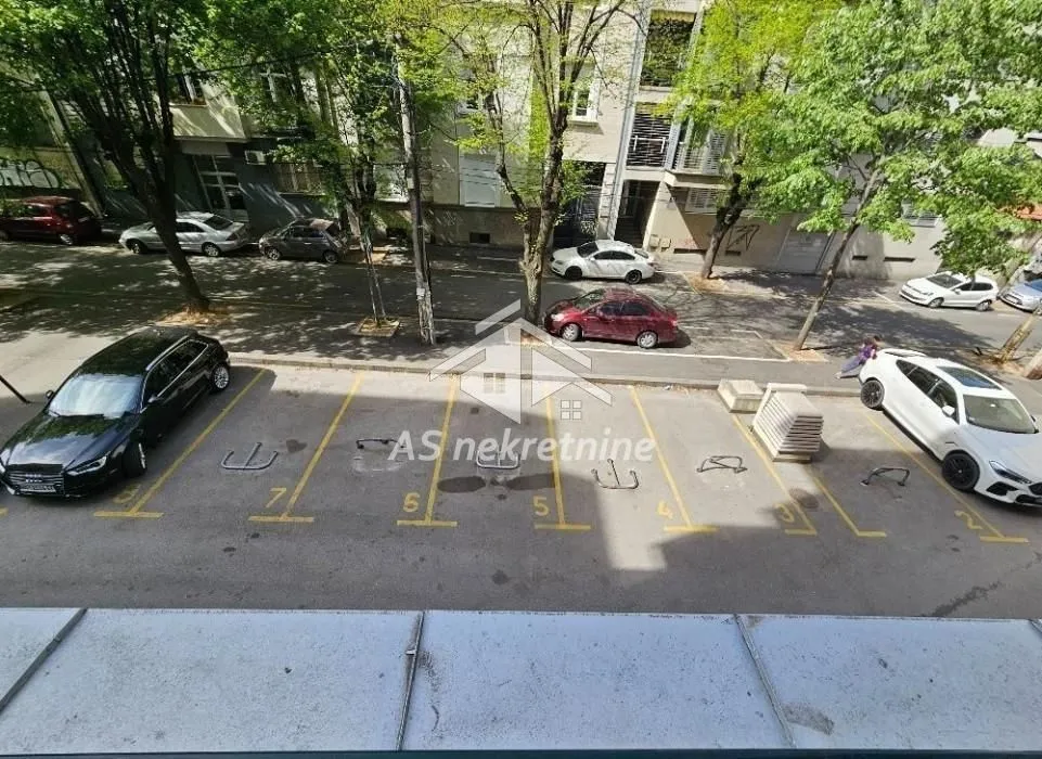Pogled sa terase na parking prostor ispred zgrade i ulicu.