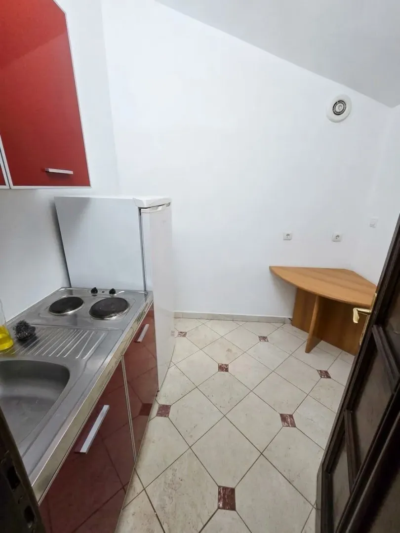 Small kitchen with a sink, stove, and refrigerator in the room.