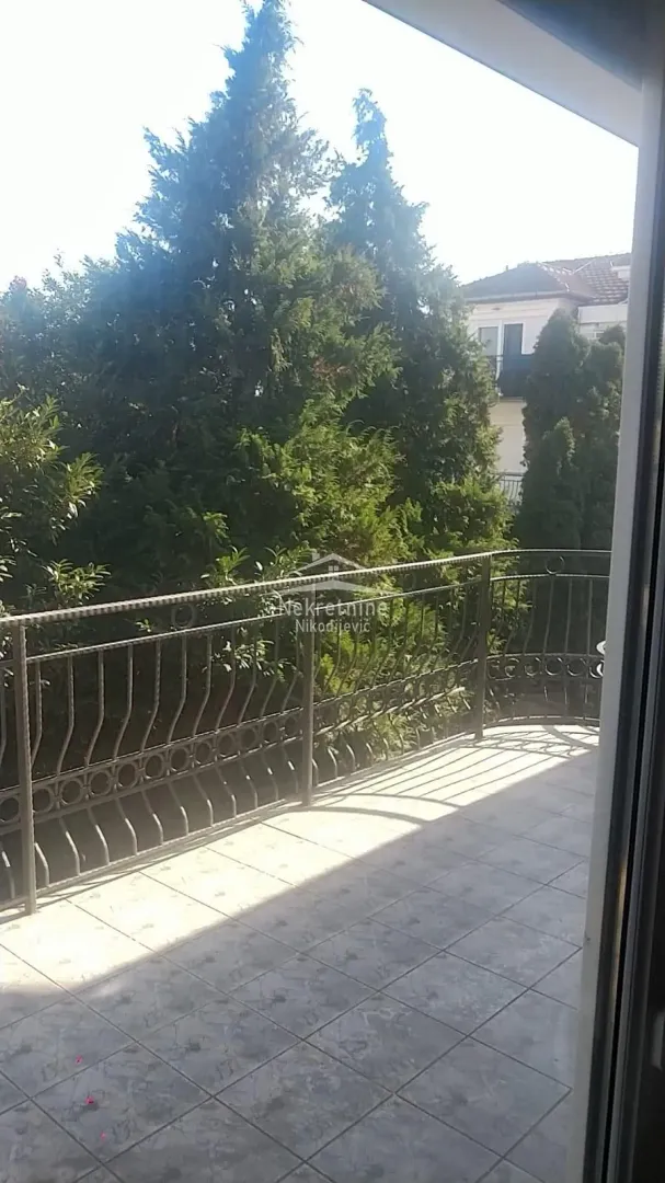 Spacious balcony with a view of greenery and surrounding buildings.