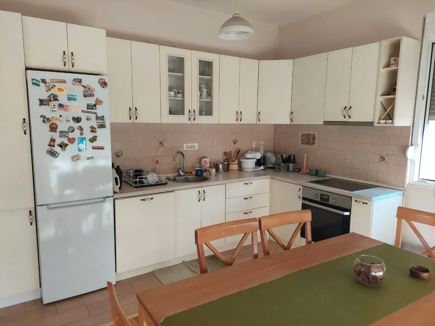 Bright kitchen with white cabinets and a dining table.