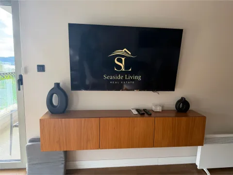 Dnevna soba sa TV-om na zidu i drvenom komodom. - image 10