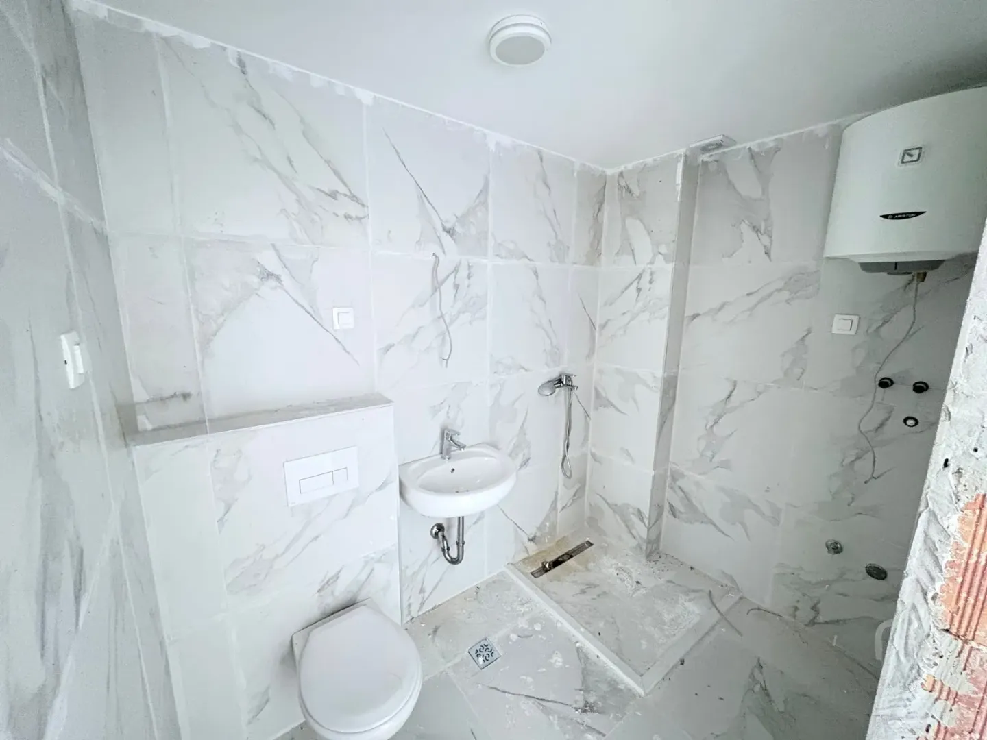 Novoopremljeno kupatilo sa mermernim pločicama, umivaonikom i wc šoljom.