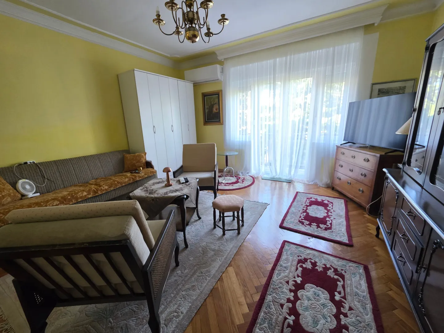 Furnished living room with sofa set, wooden floor and large window.