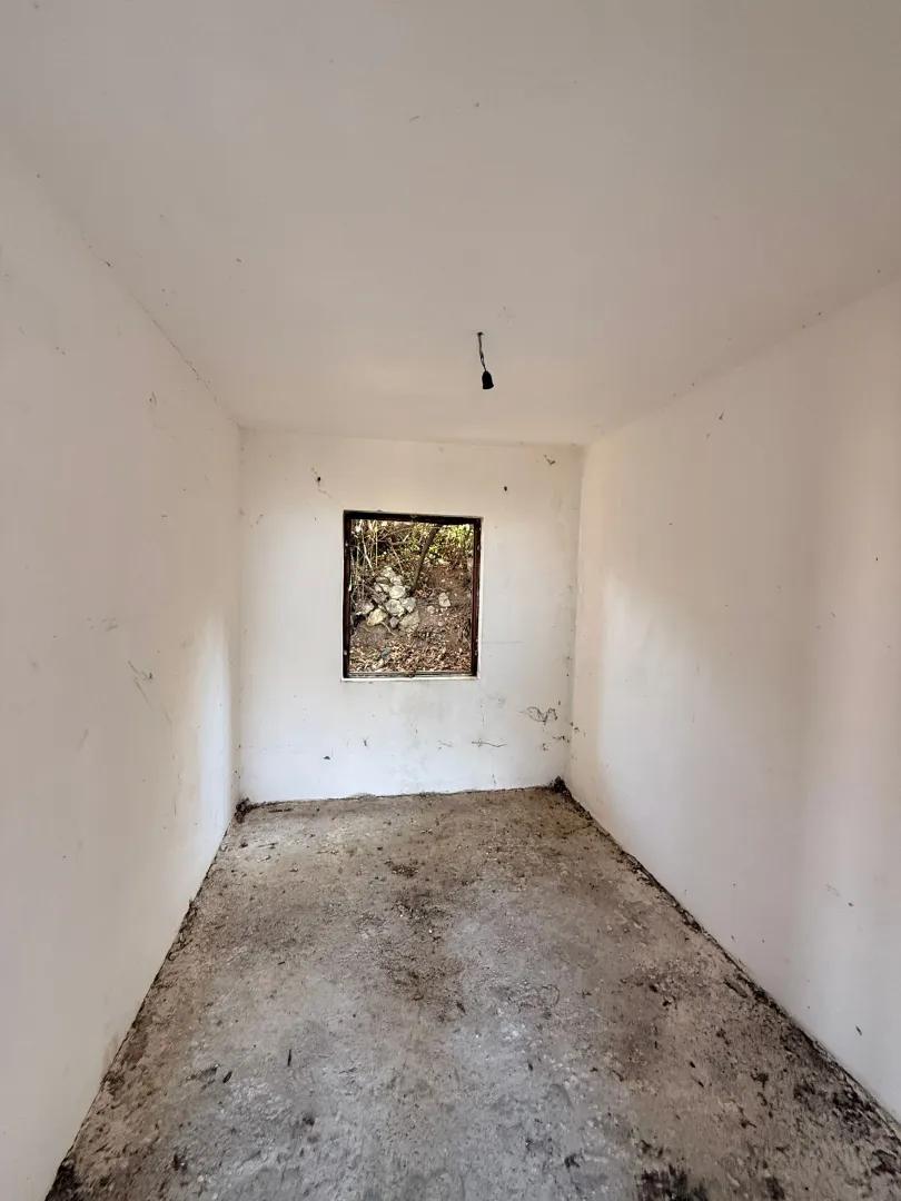 Empty room in a house under construction with plastered walls and a window.