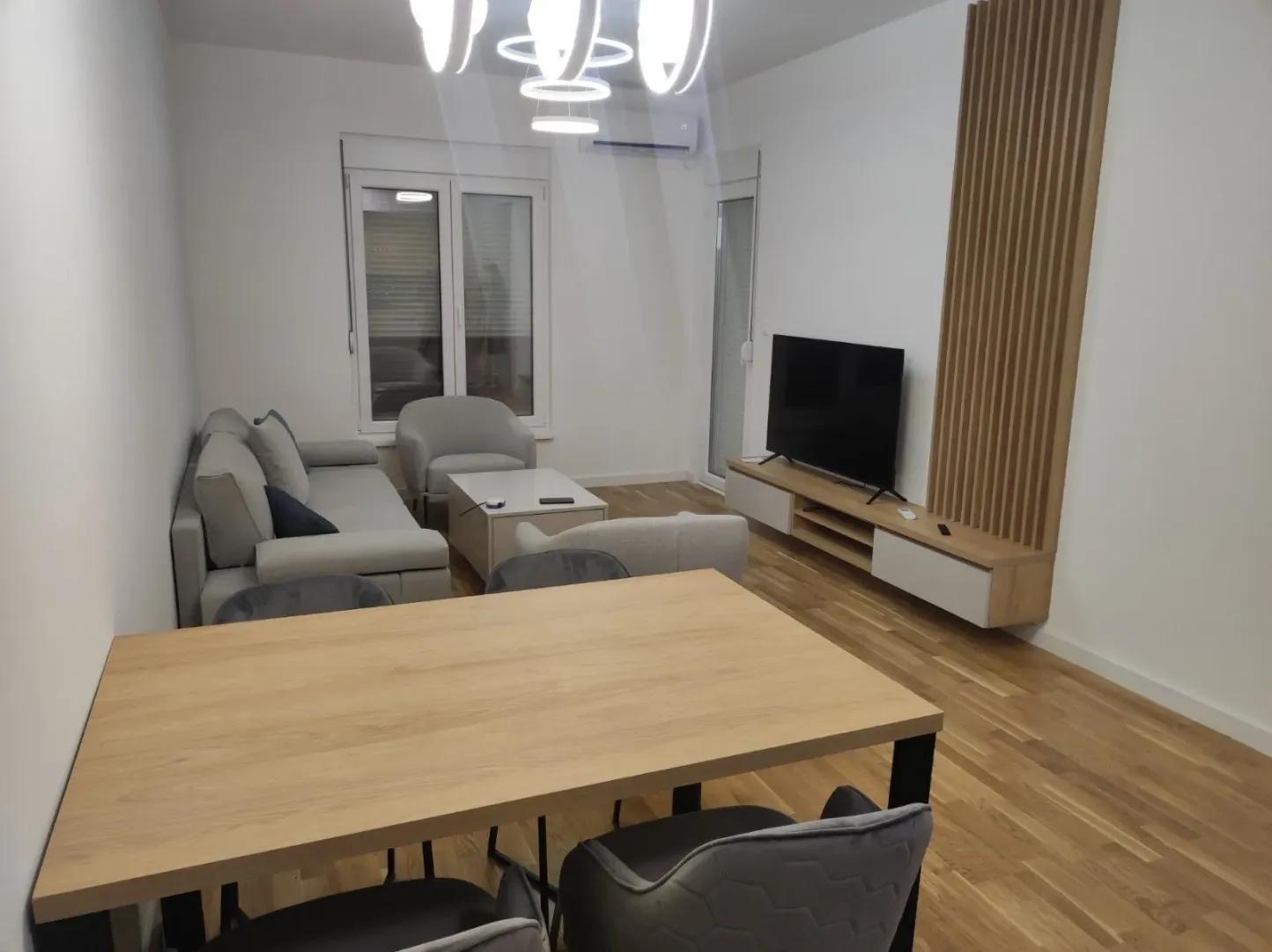 Svijetla dnevna soba sa trpezarijskim stolom, garniturom i televizorom.