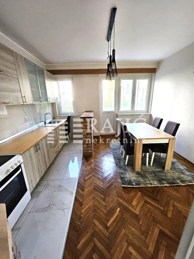 Modern kitchen with dining area and wooden flooring.