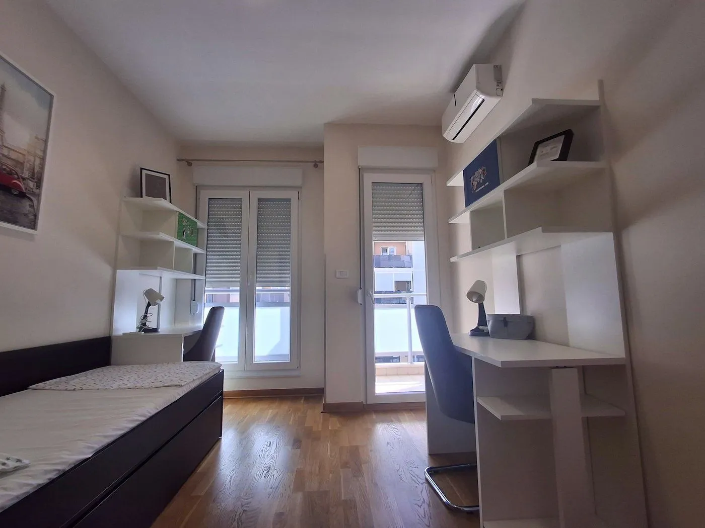 Children's bedroom with a bed, desk, and shelving.