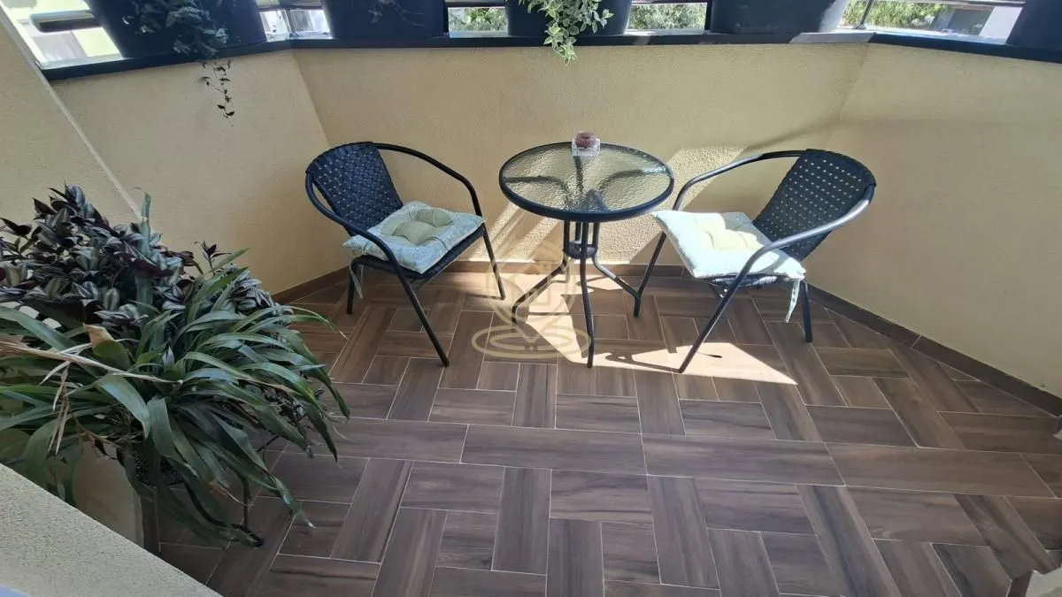 Manji namešteni balkon sa staklenim stočićem i dve stolice.