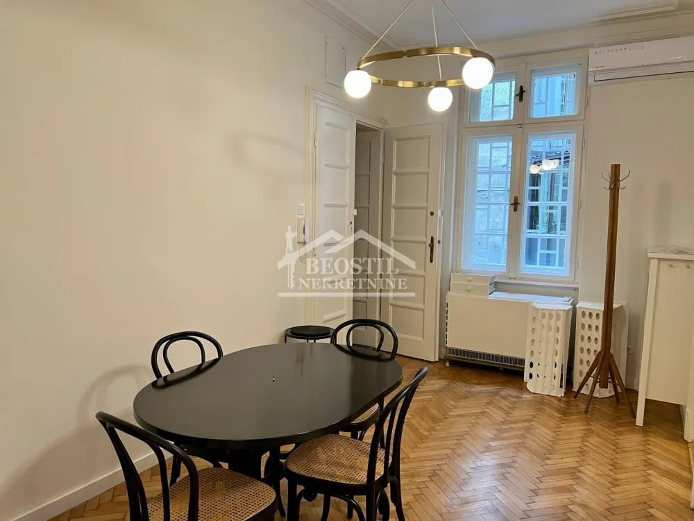 Dining area with a black table, chairs, and a modern chandelier.