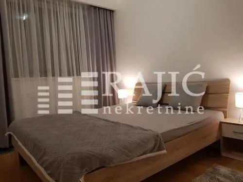 Furnished bedroom with a double bed and a window with curtains.
