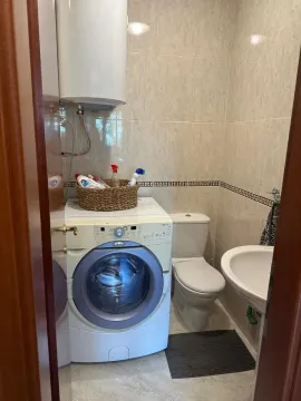 Smaller bathroom with a shower, sink, and washing machine. - image 13