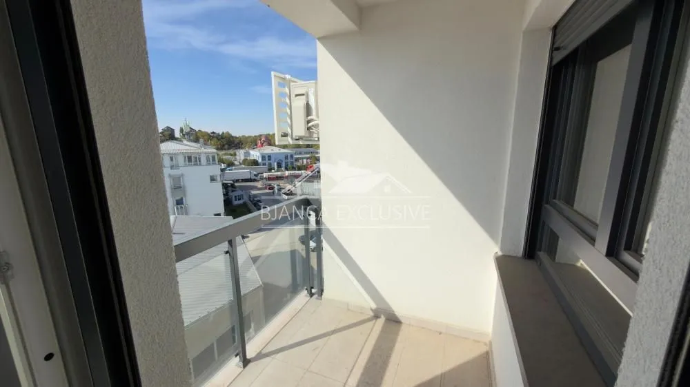 Manji natkriveni balkon sa staklenom ogradom i pogledom na ulicu.