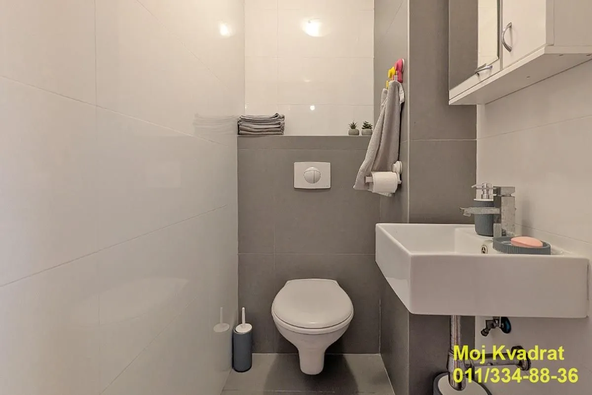 Small bathroom with a toilet, washbasin, and grey tiles.