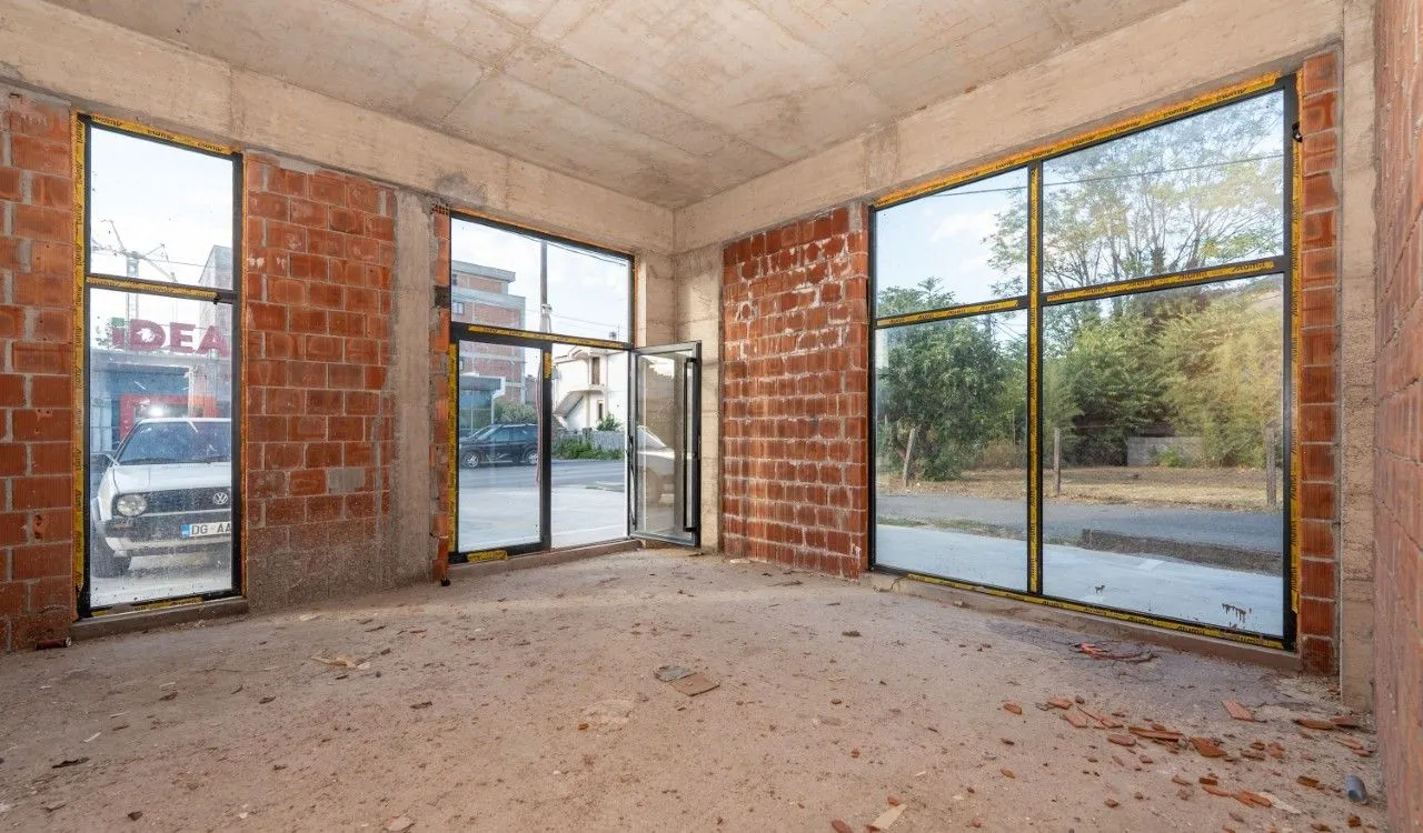Unfinished room under construction with large glass surfaces and brick walls.