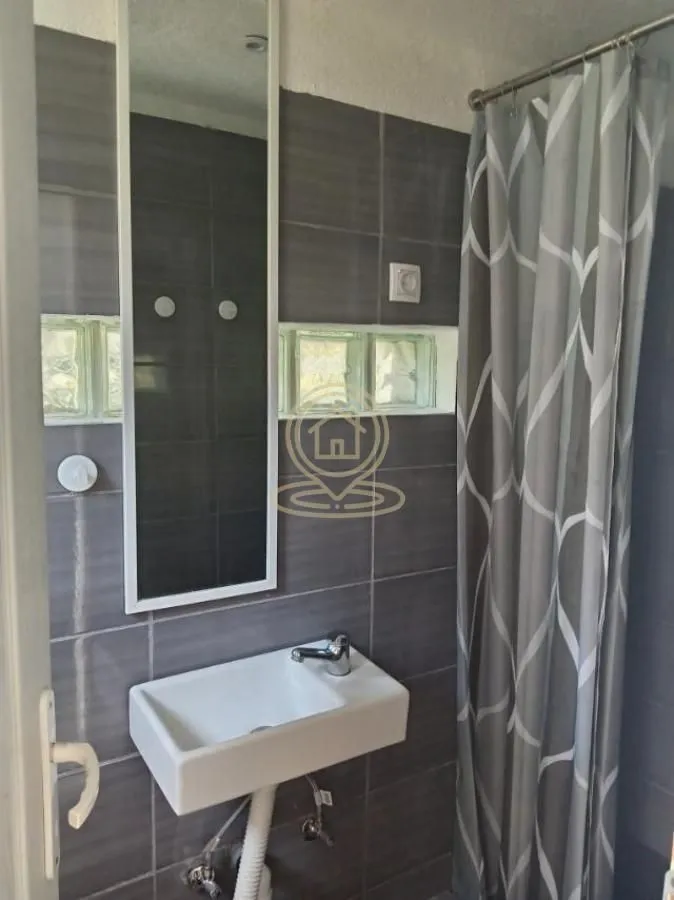 Smaller bathroom with a washbasin, mirror and shower cabin.