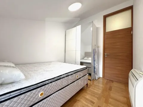 Spavaća soba sa bračnim krevetom, bijelim garderoberom sa ogledalom i drvenim podom. - image 8
