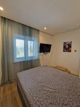Spavaća soba sa bračnim krevetom, prozorom sa zavjesama i zidnim televizorom. - image 10