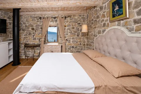 Rustic bedroom with stone walls and a sea view through the window. - image 9