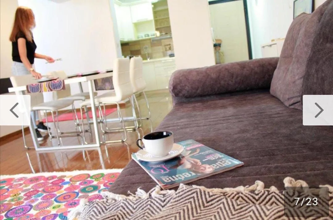 Living room with a sofa and a view towards the dining area and kitchen, with a person visible.
