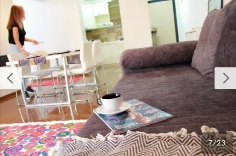Living room with a sofa and a view towards the dining area and kitchen, with a person visible. - image 12