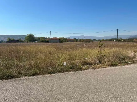 Pogled na ravno zemljište sa travom pored puta i sa kućama u pozadini. - image 4