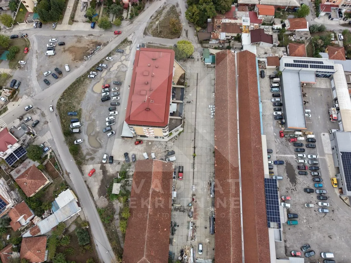 Aerial view of the buildings, yard, and surrounding area with parking spaces.