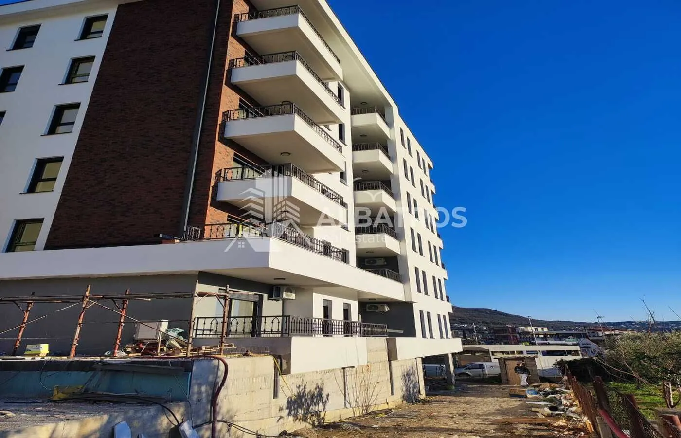 Exterior view of a multi-story residential building with balconies and a yard.