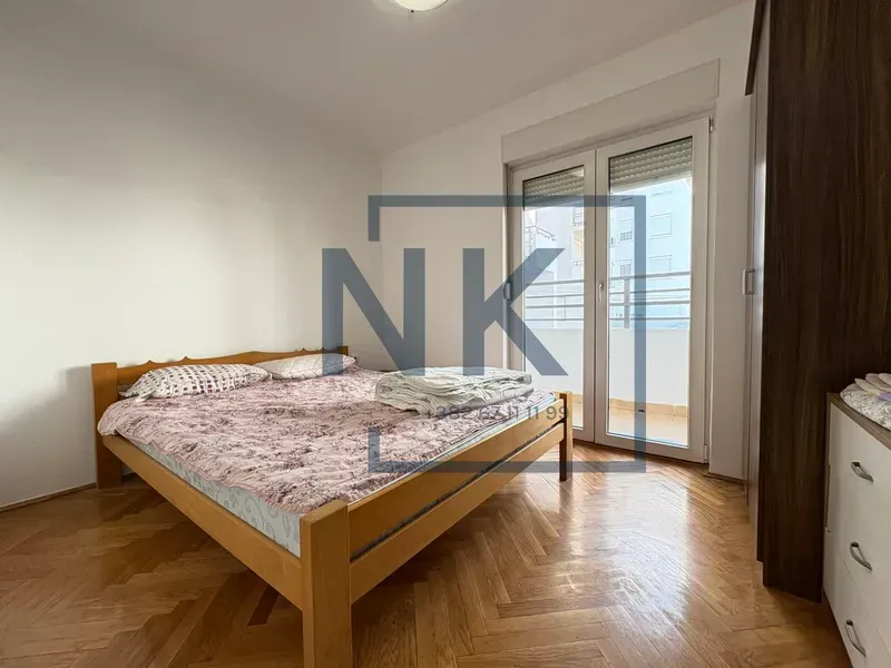 Furnished bedroom with a double bed, wooden flooring, and access to a terrace.