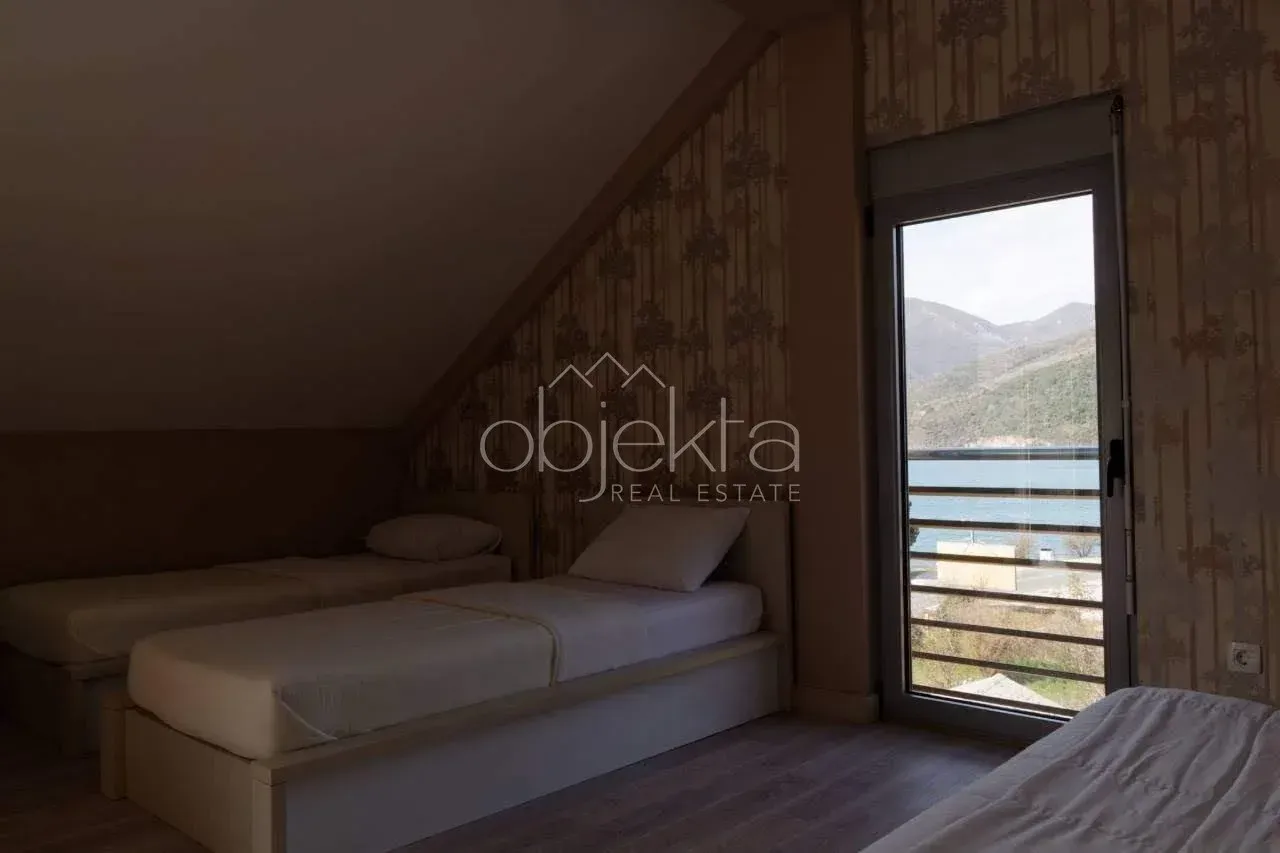 Attic bedroom furnished with several beds and a balcony door overlooking the sea.