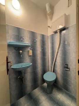 Small bathroom with blue tiles, a washbasin and a toilet. - image 13
