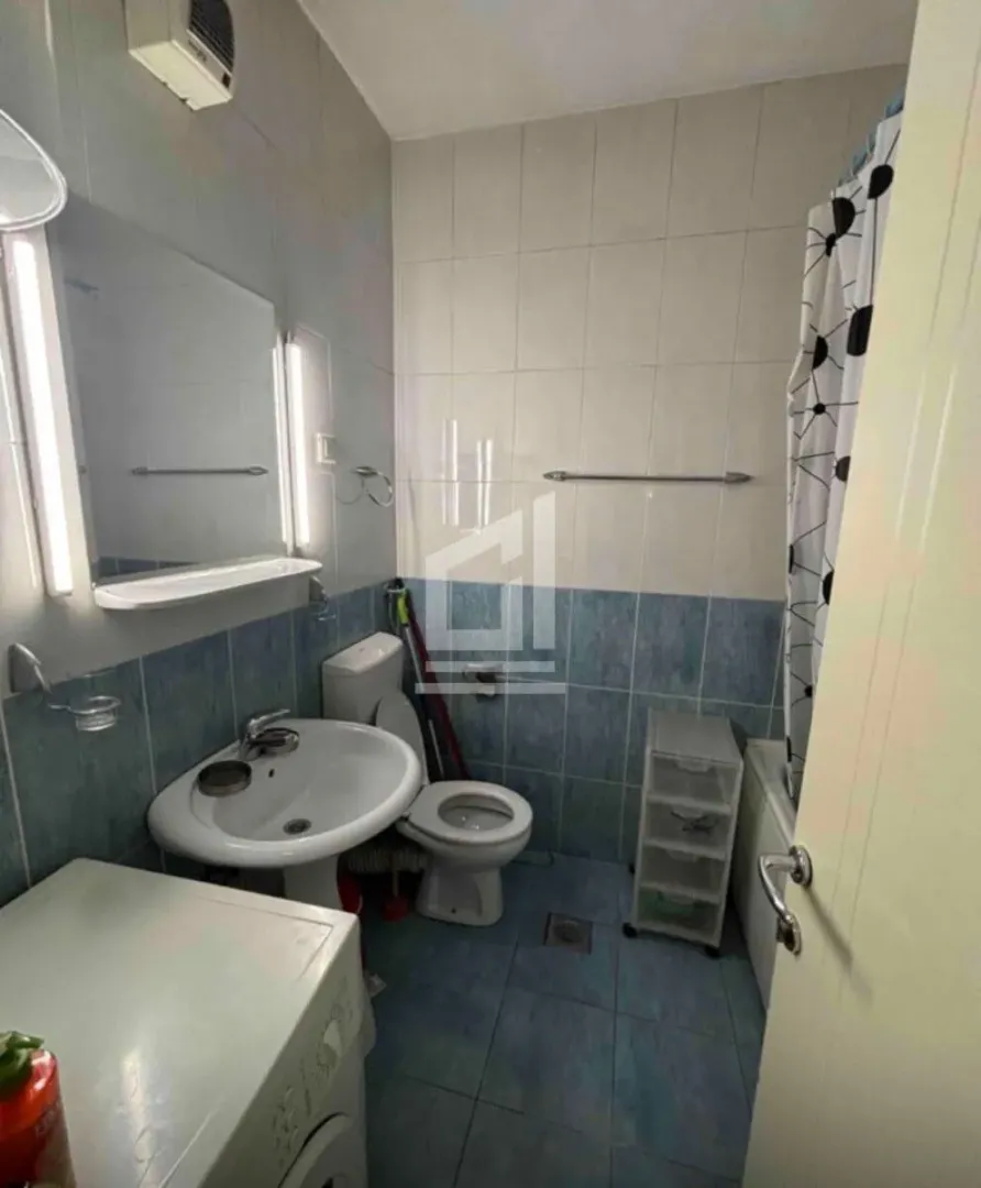 Manje kupatilo sa umivaonikom, WC šoljom, mašinom za veš i kadom sa zavesom.