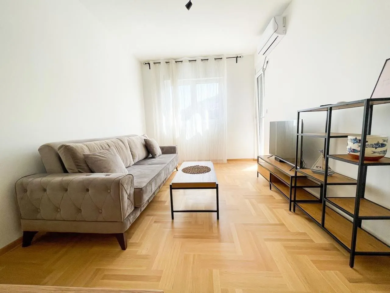 Bright living room with sofa, coffee table, and shelving units.