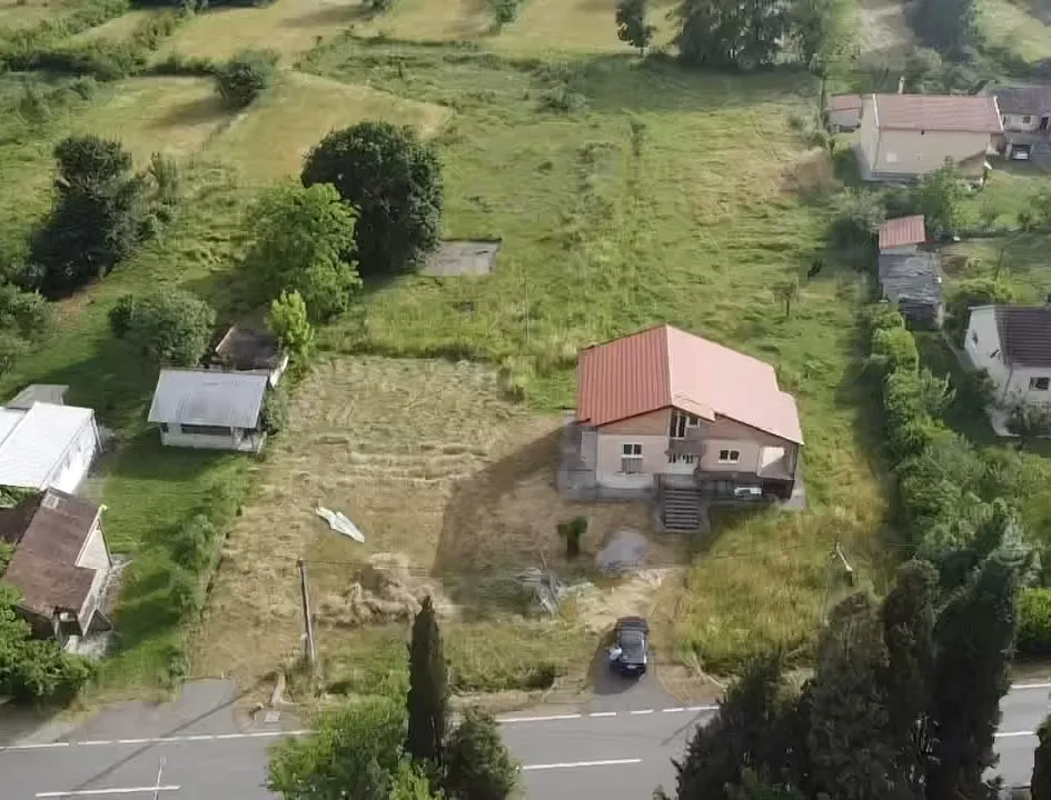 Aerial view of a house with a spacious property next to a road.