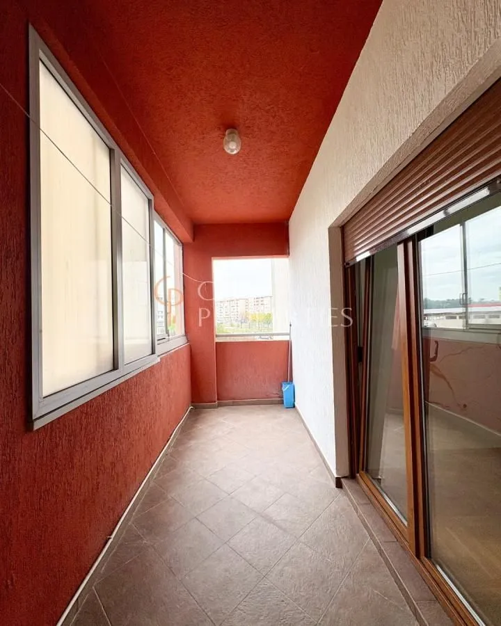 Covered balcony with tiled floor and large glass windows.