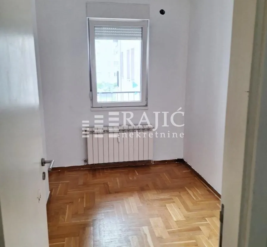 Empty room with parquet flooring and a window.