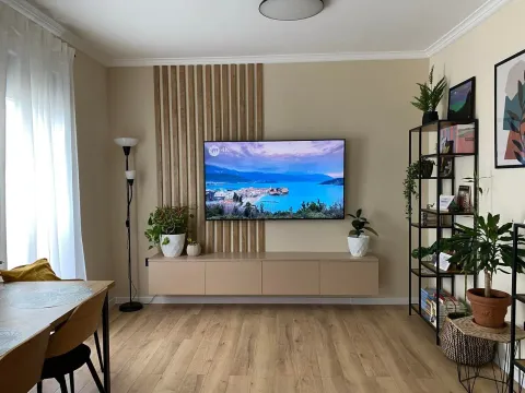 Living room with a TV, wooden wall panels, and a bookshelf. - image 6