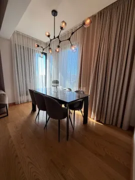 Dining room with a table, chairs, and modern chandelier. - image 4