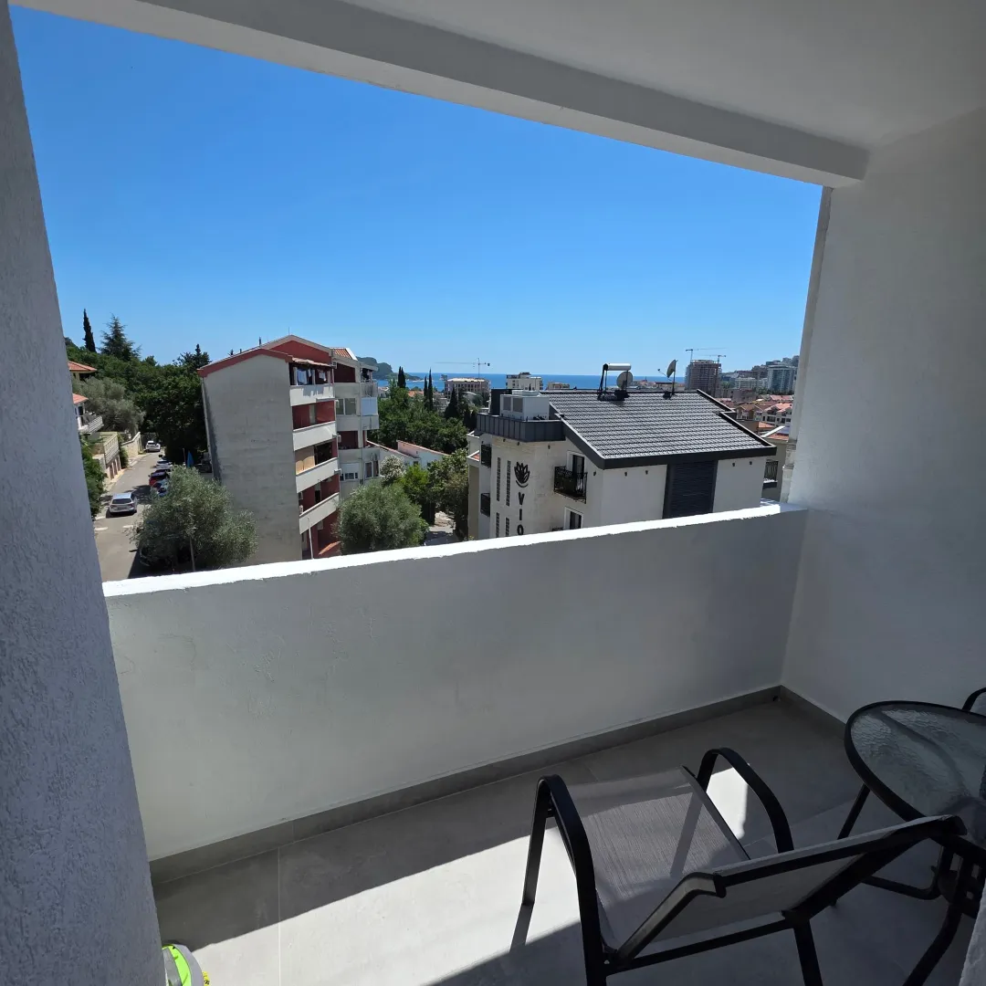 Covered terrace with seating furniture and a view of the city and sea.