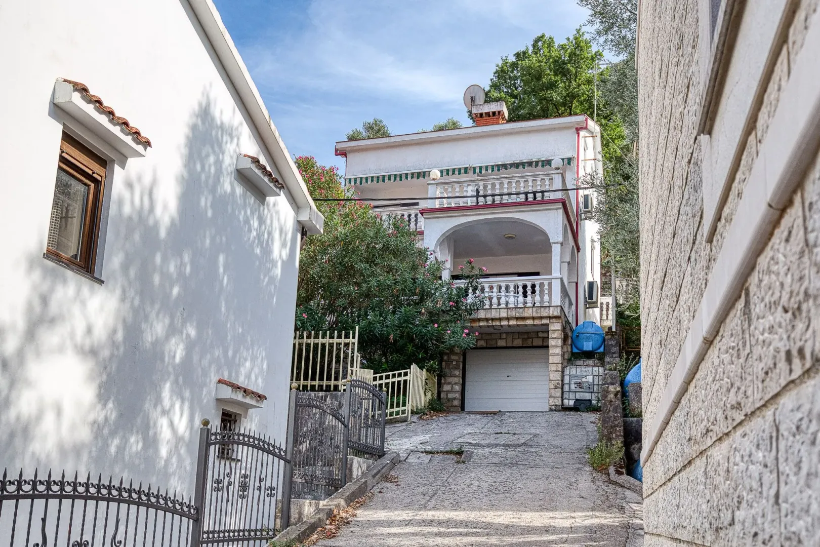 Pogled na fasadu i dvorište kuće sa prilazom i garažom.