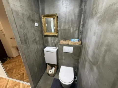 Manje kupatilo sa betonskim zidovima, umivaonikom i toaletom. - image 2
